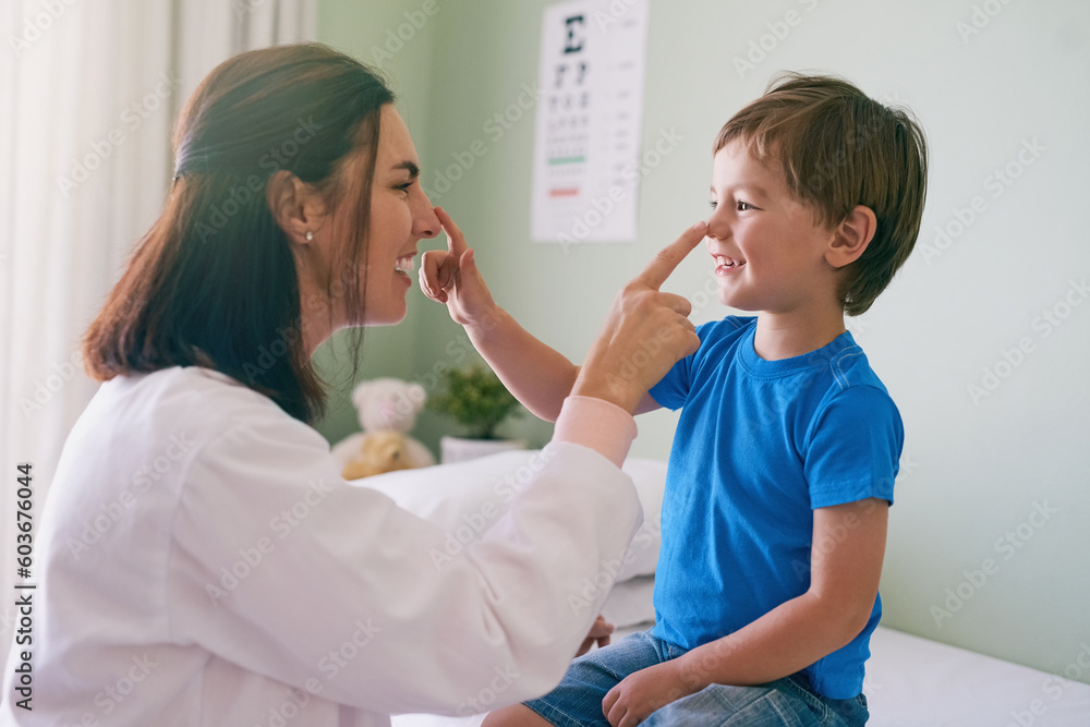 Fototapeta premium Woman doctor, playing and child fun at a hospital for healthcare and medical consultation. Smile, trust and pediatrician touch nose with a laugh and happiness in a clinic with boy patient with exam