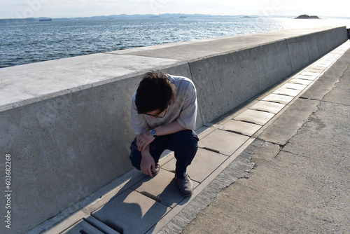 A man peeking into the gutter of the sea breakwater