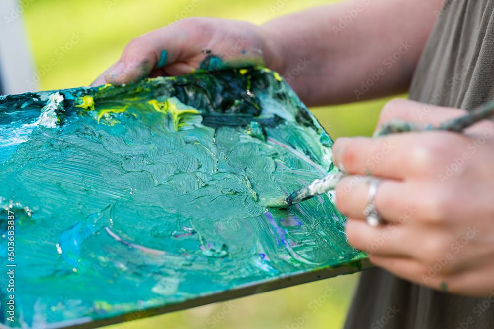 Artist holding messy paint palette tray for mixing colours Artist holding messy paint palette tray for mixing colours