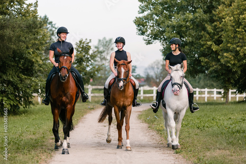 Three female riders riding horses along the trail. Recreation and leisure activity concepts. © 24K-Production