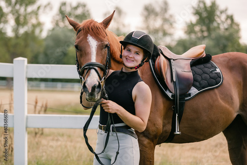 Young female jockey in helmet petting her horse in countryside