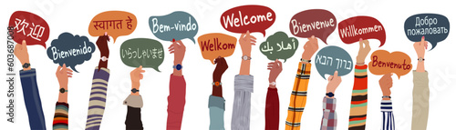 Raised arms and hands of multicultural people from different nations and continents holding speech bubbles with text -welcome- in various international languages.Communication.Equality
