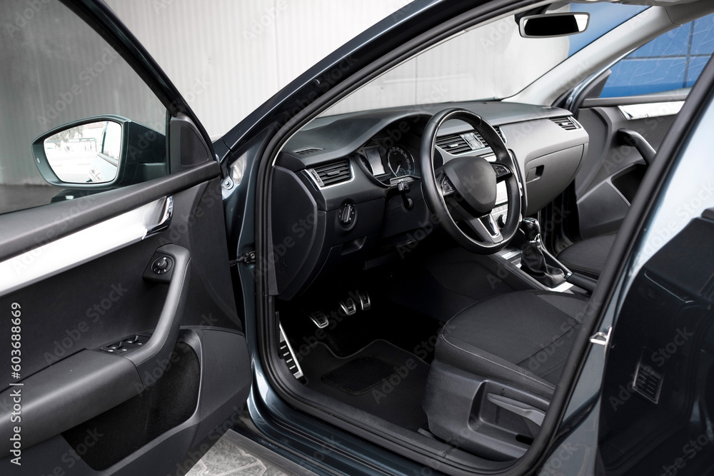 Modern black car interior, leather steering wheel, climate control, navigation, deflectors on the car panel. Details interior. 