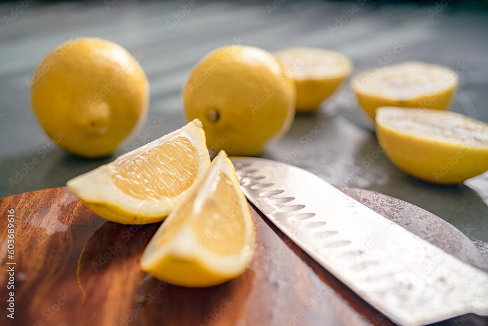 Cutted Sicilian lemons on wooden board next to a knife and other lemons arranged in the background. Cutted Sicilian lemons on wooden board next to a knife and other lemons arranged in the background.