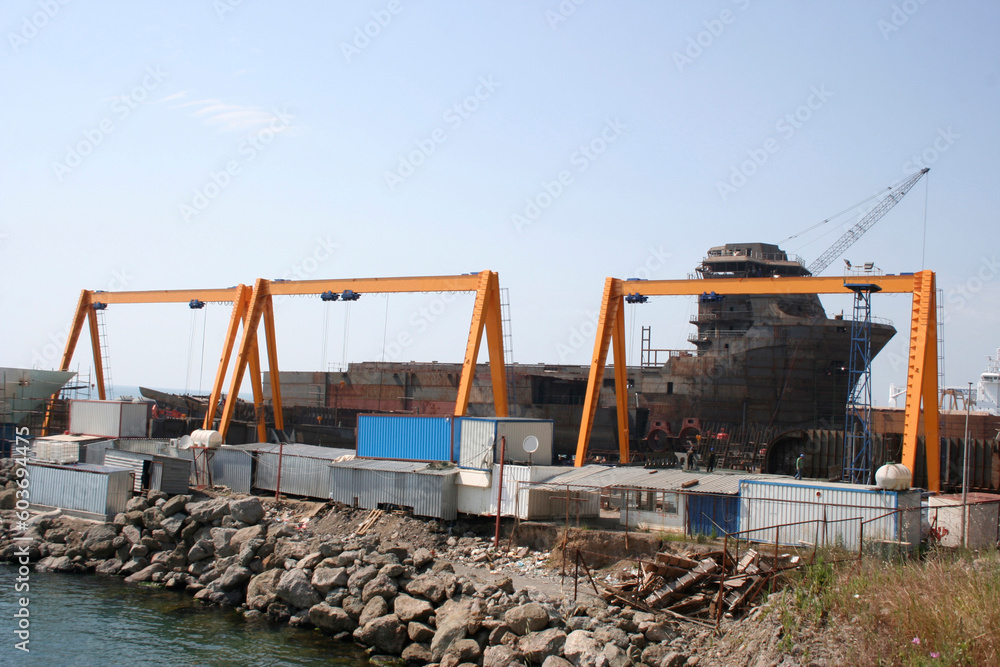 Fototapeta premium Shipbuilding pier and crane. Workers working on the pier.