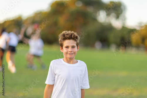 one young boy in white tee shirt with other kids out of focus playing in the background photo