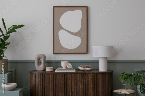 Interior design of cozy living room interior with mock up poster frame, wooden sideboard stylish lamp, modern sculpture, plants and personal accessories. Home decor. Template. photo