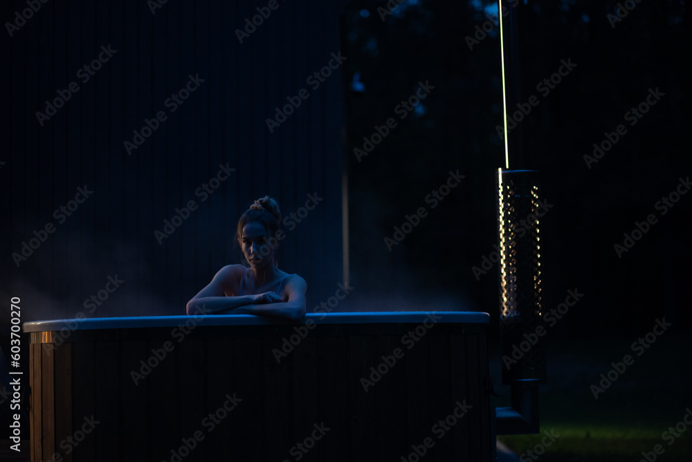 Fototapeta premium Woman relax in outside hot tub at night. Cinematic view