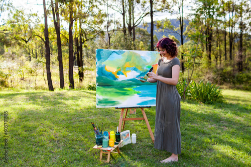 Young female artist mixing paint for artwork on canvas photo