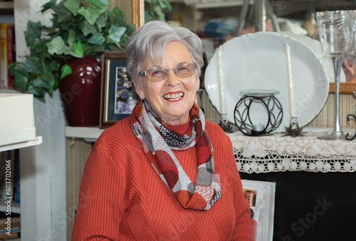 Portrait of older lady smiling at the camera standing in an op shop photo