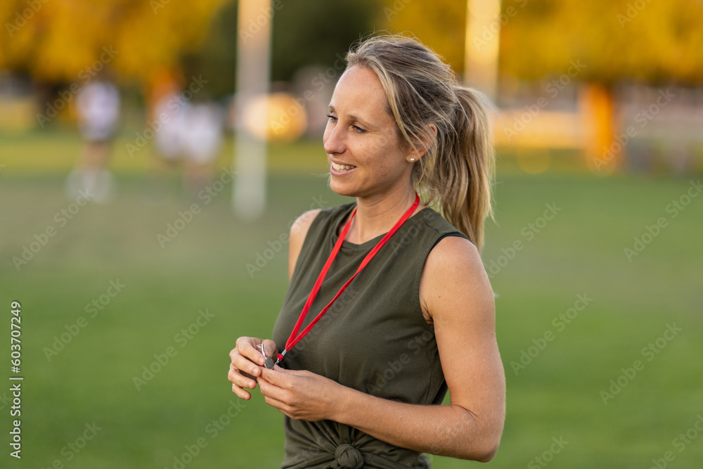 female sports coach with pony tail holding whistle on red tape around her neck female sports coach with pony tail holding whistle on red tape around her neck