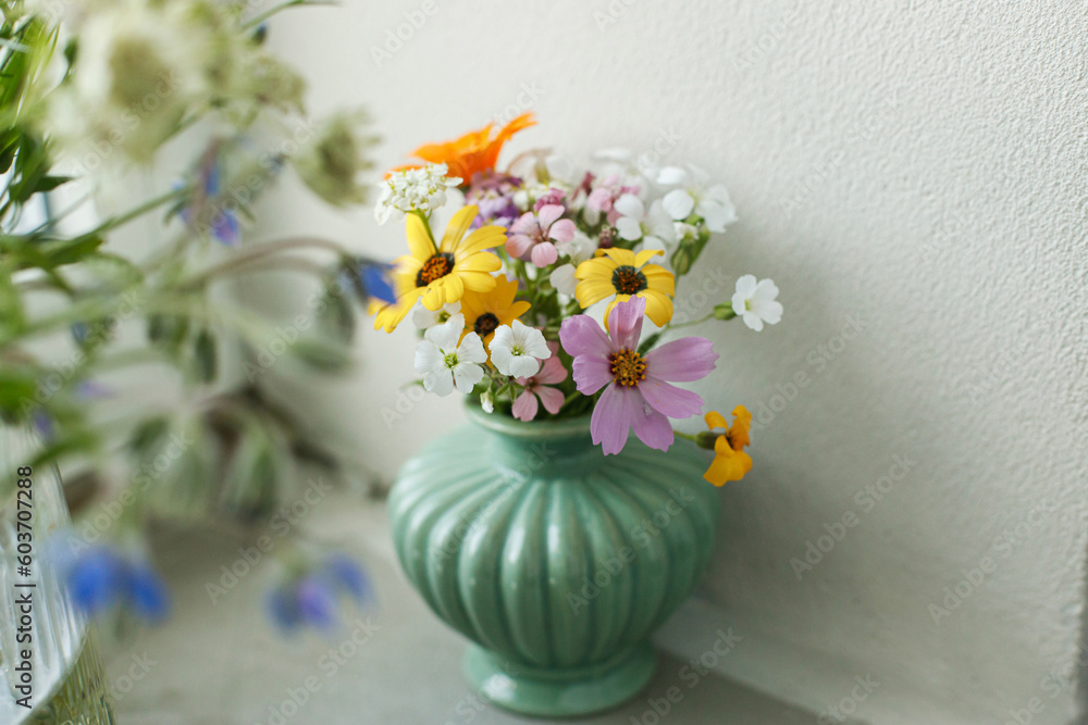 Stylish colorful wildflowers bouquet on tile shelf on rustic wall background. Beautiful summer flowers in vase gathered from garden, floral arrangement in modern room in home Stylish colorful wildflowers bouquet on tile shelf on rustic wall background. Beautiful summer flowers in vase gathered from garden, floral arrangement in modern room in home