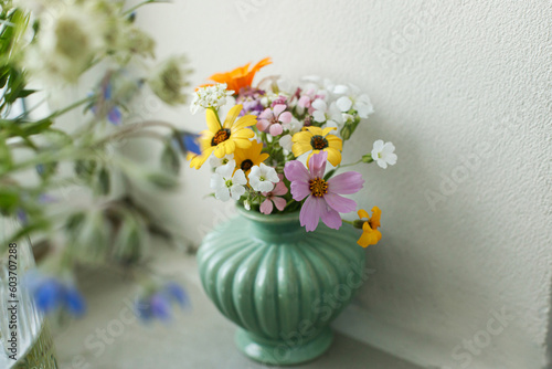 Fototapeta Naklejka Na Ścianę i Meble -  Stylish colorful wildflowers bouquet on tile shelf on rustic wall background. Beautiful summer flowers in vase gathered from garden, floral arrangement in modern room in home