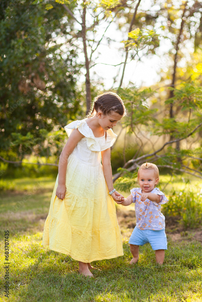 Two girls holding hands and walking together on rural property in afternoon Two girls holding hands and walking together on rural property in afternoon