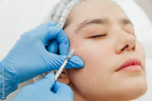 Close-up of the hands of a beautician injecting Botox into a woman s forehead. Correction of forehead and eye wrinkles with botulinum toxin.