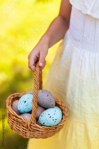 Child with wicker basket of blue and grey speckled Easter eggs