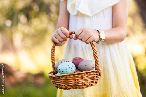 child holding out basket of speckled easter eggs photo