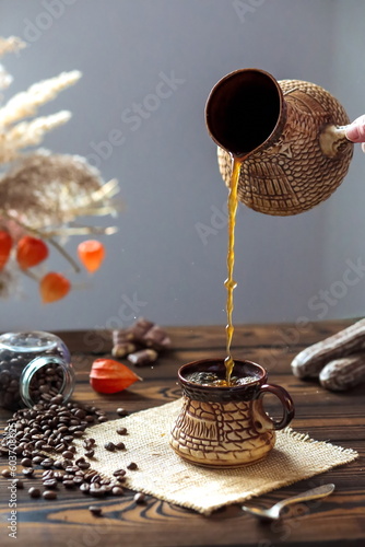 Hot coffee pours from a retro turkey into a cup on the kitchen table. Rustic style