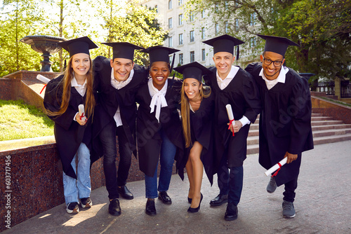 Fotografiet Group of multiracial students pose cheerfully for graduation photo outdoors with diplomas