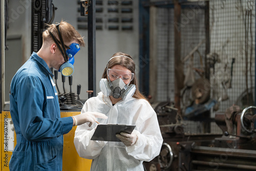 emergency pollution factory concept. The engineer, wearing a Mechanic Jumpsuit and ppe and gas mask, looks at the camera with his arms crossed.
