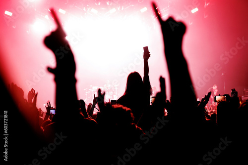 Girl on shoulders silhouette. Happy people with raised hands at a music concert.