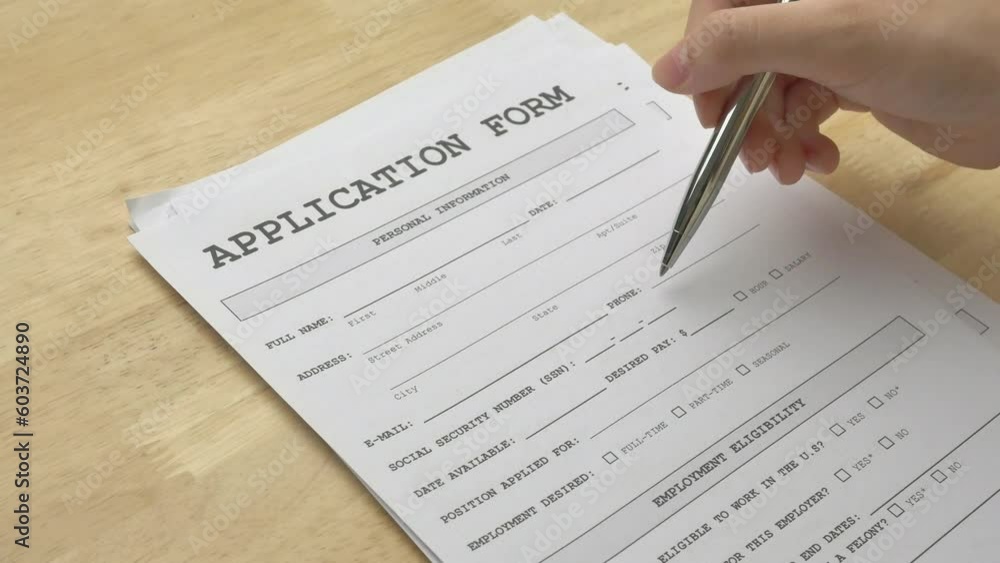 A woman's hand holding a pen and pointing to the application form, pre-checking details before filling in the personal information. Concepts of job application, human resources, employment, business. A woman's hand holding a pen and pointing to the application form, pre-checking details before filling in the personal information. Concepts of job application, human resources, employment, business.