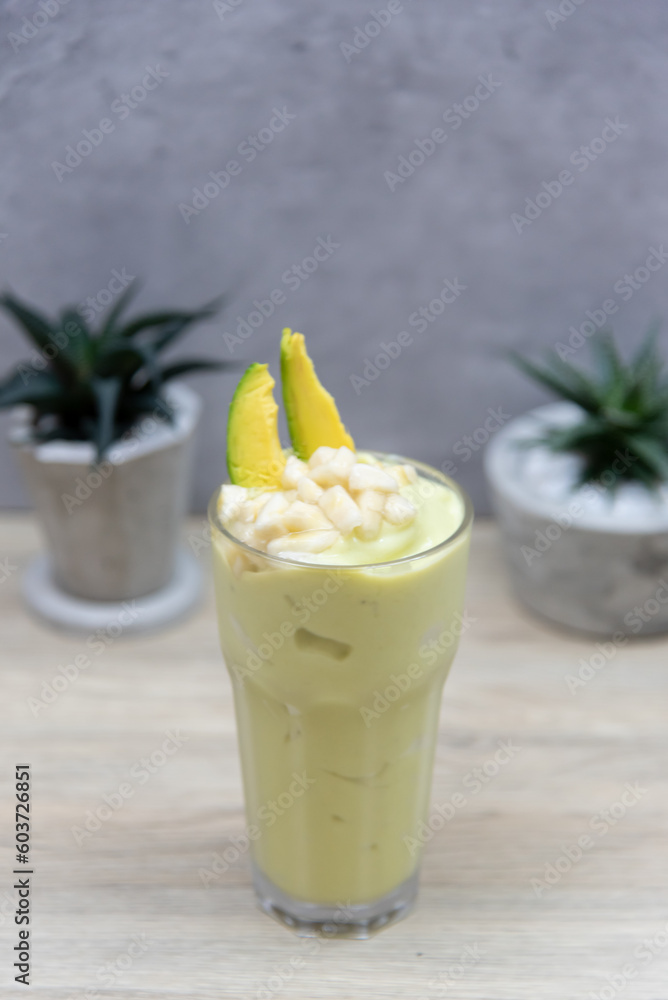 Glass of avocado smoothie on wooden table Glass of avocado smoothie on wooden table