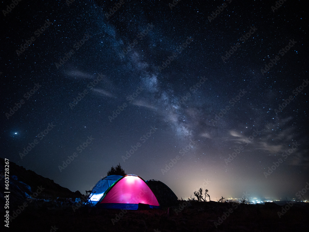 Acampada bajo las estrellas en la montaña y tiendas de campaña con luz.
