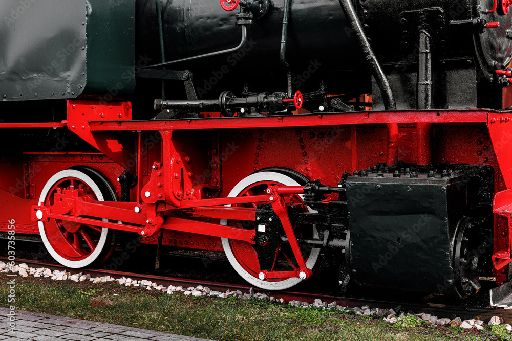 Naklejka premium Vintage steam train with vibrant red metal wheels.