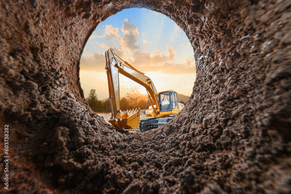 Crawler excavator are digging soil in the tunnel construction site. With a sunset background Crawler excavator are digging soil in the tunnel construction site. With a sunset background