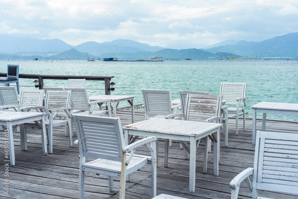 White wooden chairs and tables on wooden pier of south china sea in Vietnam