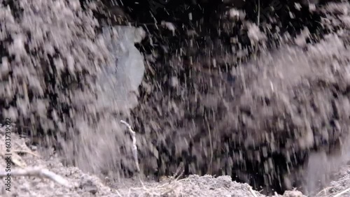 Close up and super slow motion of gas soil tiller while starting rotating and pulverize soil.