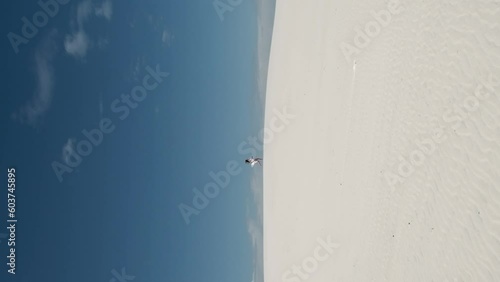 Silhouette Young woman running through the desert. Brunette with long flowing hair. The dress flutters in the wind. Blue sky. footprints in the sand photo