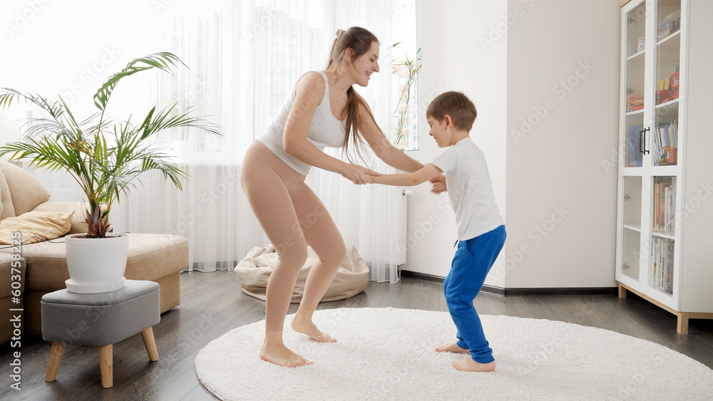 Happy cheerful mother with little son dancing and having fun on carpet in living room Happy cheerful mother with little son dancing and having fun on carpet in living room