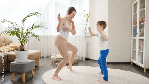Cheerful mother and 6 year old son dancing at home together. Family having fun together, listening music, active lifestyle, parenting and child development
