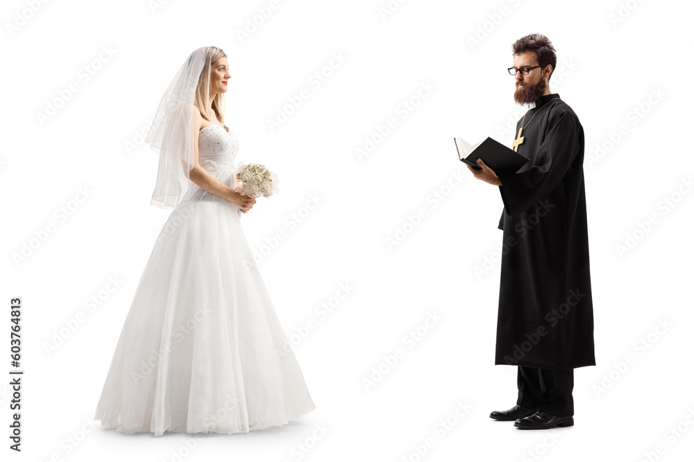 Full length profile shot of a bride standing with a priest holding a bible