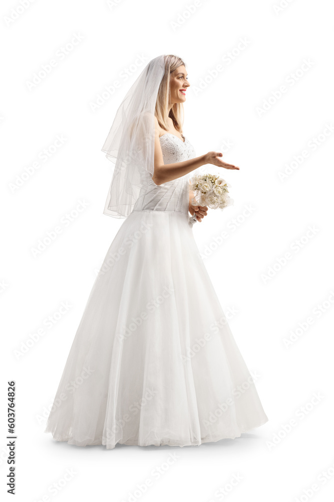 Full length profile shot of a bride with a veil holding a bridal bouquet and gesturing with hand Full length profile shot of a bride with a veil holding a bridal bouquet and gesturing with hand