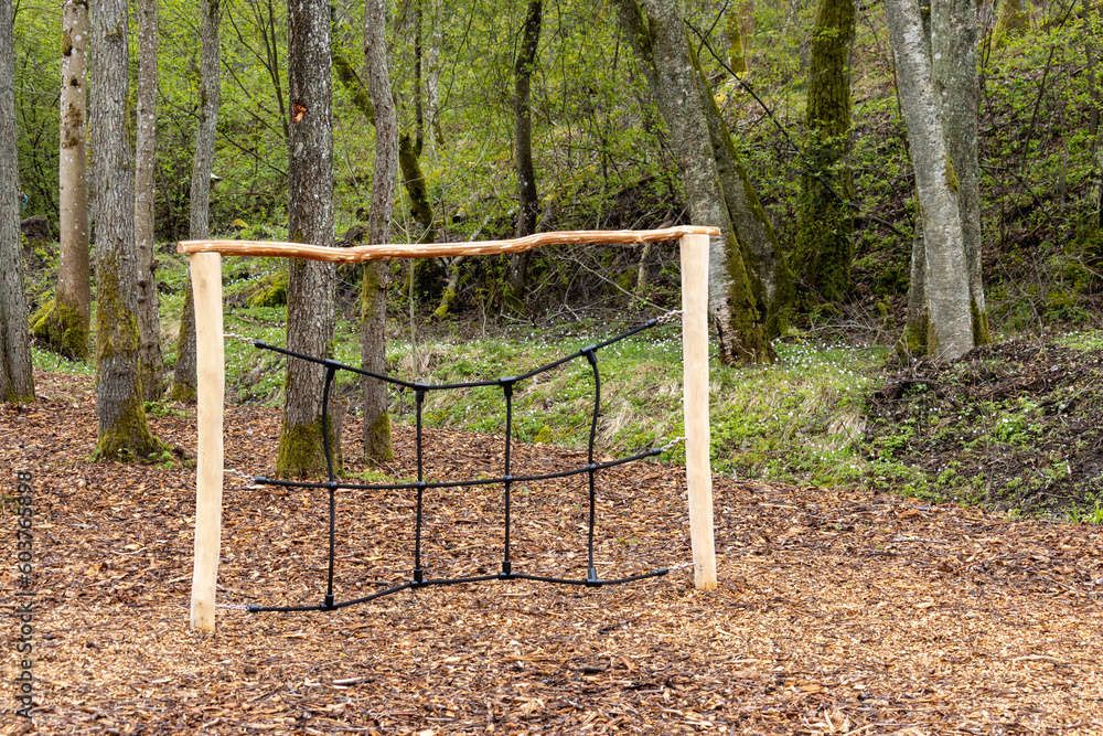 Wooden climbing frame with net in childrens outdoor playground.