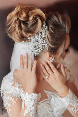 Cropped photo. Blonde bride. Beautiful hands with a lace sleeve, beautiful beading and silver decoration on the bride's hair. Wedding portrait. French manicure