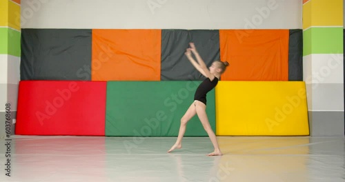 A girl gymnast practicing in a room with colorful mats