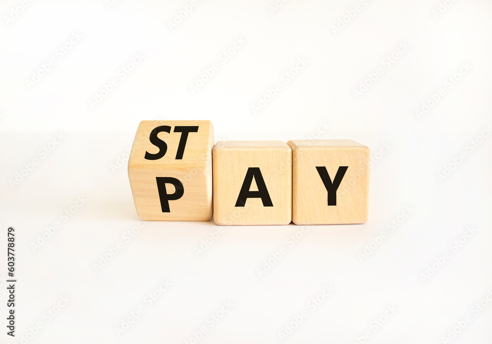 Stay and pay symbol. Businessman turns wooden cubes and changes the word Stay to Pay. Beautiful white table white background. Copy space. Business and stay and pay concept. Stay and pay symbol. Businessman turns wooden cubes and changes the word Stay to Pay. Beautiful white table white background. Copy space. Business and stay and pay concept.