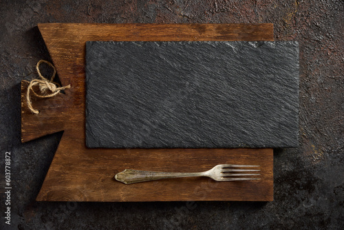 Black slate on a brown cutting board - top view. Empty space for menu or recipe.