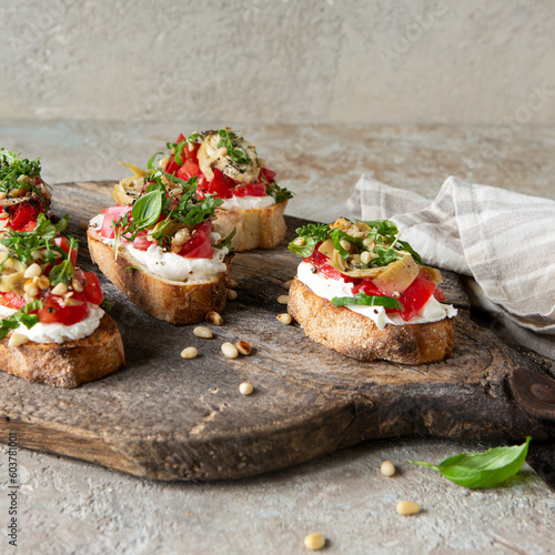 bruschettas with cream cheese, tomatoes and artichokes on a wooden board