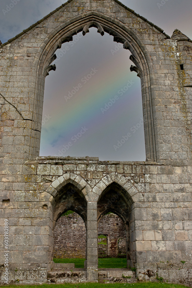 Abbey window ruin with a rainbow in the inside. British religious history concept.