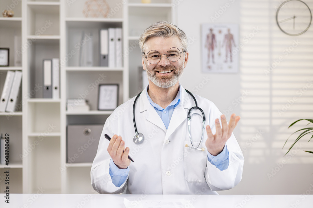 Portrait of a senior male doctor and teacher who conducts online training for medical university students via video call. Reads a lecture, conducts a course, takes exams remotely. Portrait of a senior male doctor and teacher who conducts online training for medical university students via video call. Reads a lecture, conducts a course, takes exams remotely.