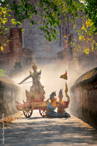 Vertical image of Khon or traditional Thai classic masked from the Ramakien as character of human dance on traditional chariot in front of ancient building with mist or fog.