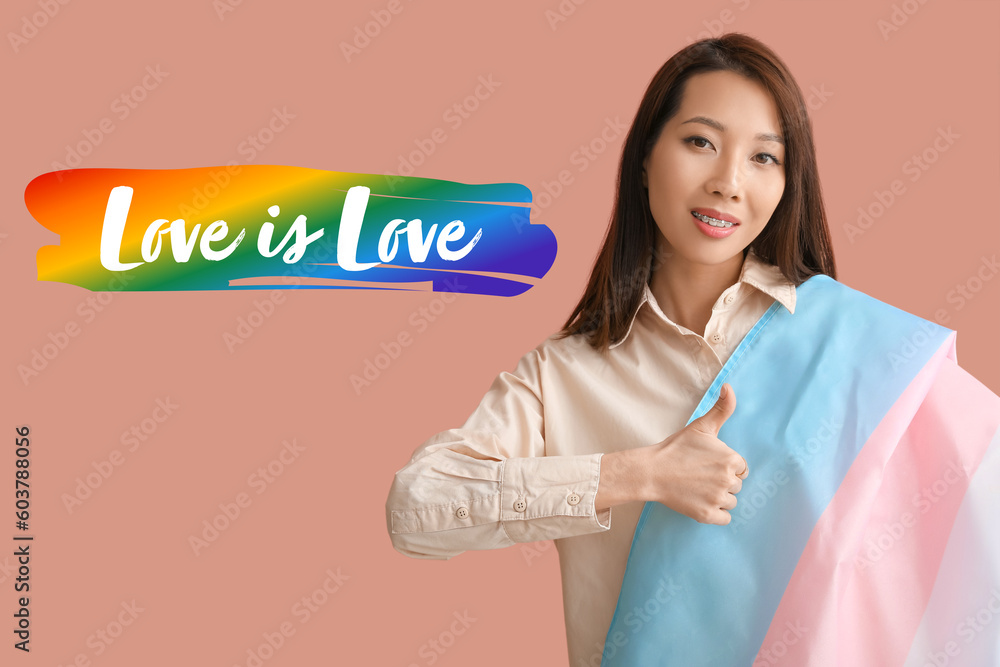 Young Asian woman with transgender flag on beige background. Pride Month Young Asian woman with transgender flag on beige background. Pride Month