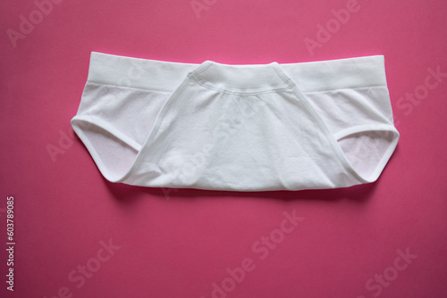 Step 2 folding the white panties on a pink background, fold the panties in half, on top. Organization and storage of underwear. Organization solution. Women's high rise mini small stylish panties