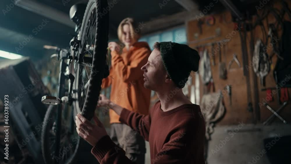 Dad and son work in the garage, they check if the chain on the bike is working Dad and son work in the garage, they check if the chain on the bike is working