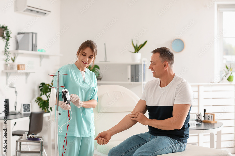 Mature man with nurse after donating blood in clinic Mature man with nurse after donating blood in clinic